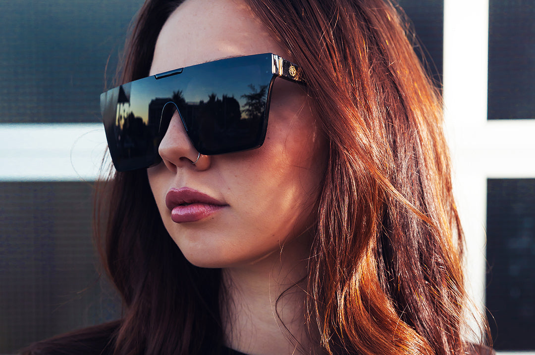 Women outside wearing the Heat Wave Visual Clarity Sunglasses with black frame and ultra black lenses.