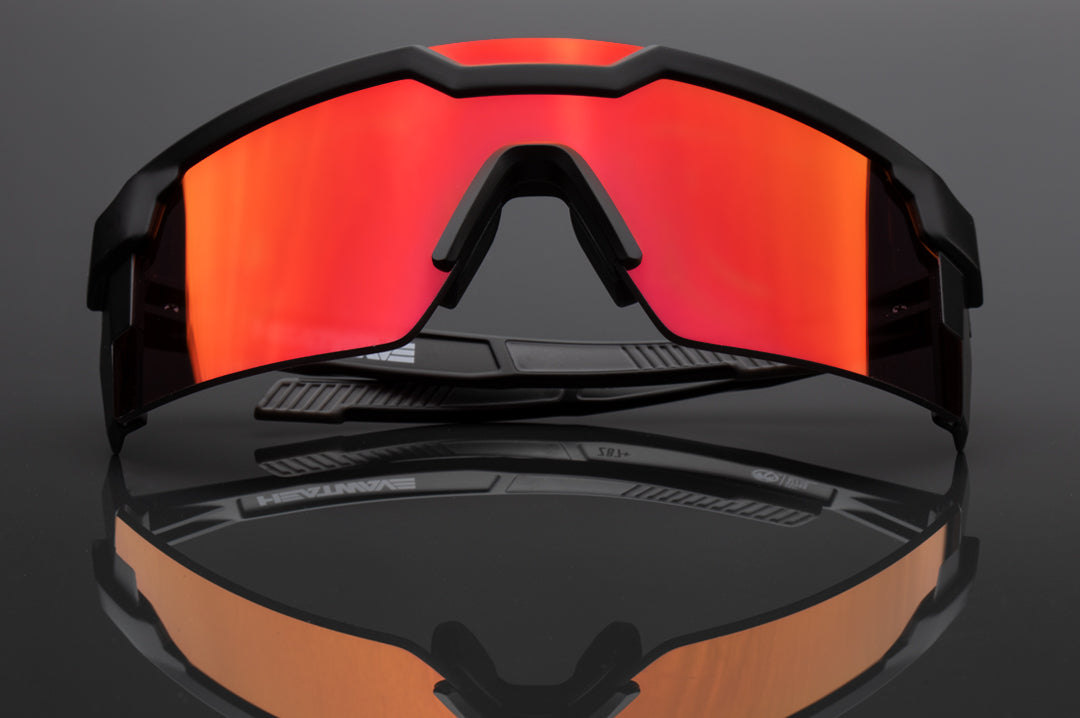 A pair of Heat Wave Visual Future Tech Sunglasses with black frame and firestorm red lens sitting on a table.