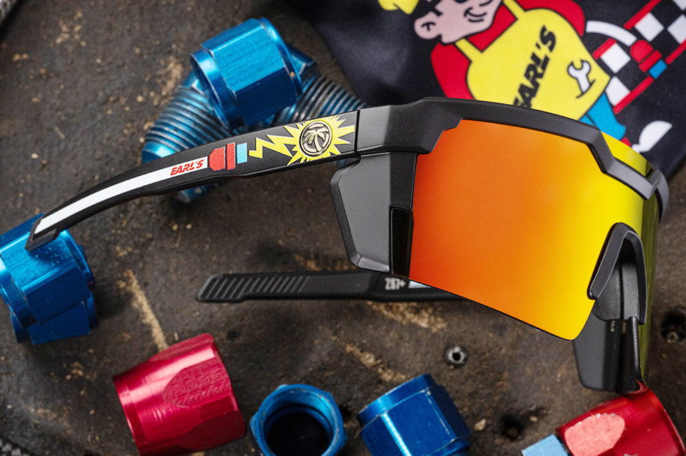 Surrounded by AN Fittings is the Heat Wave Visual Future Tech Sunglasses with black frame, Earl's x HWV collab and sunblast orange yellow lenses.