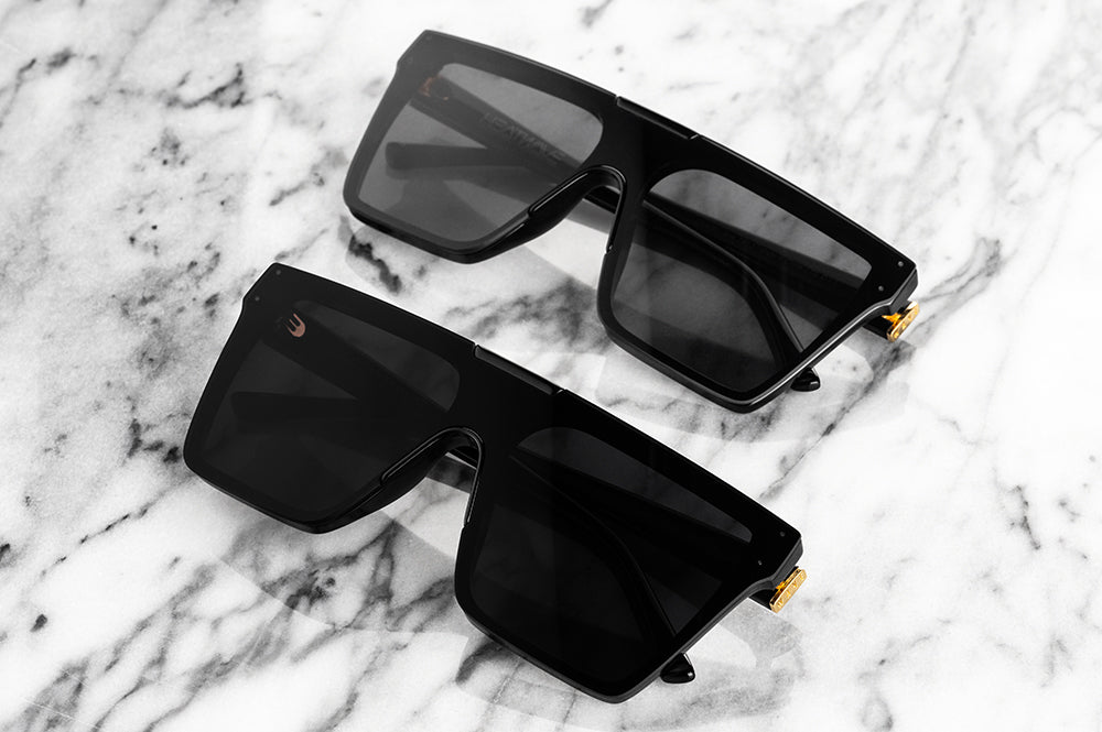 Lying on a table is the Clarity Ultra Black Sunglasses in comparison with the Clarity Black Sunglasses.