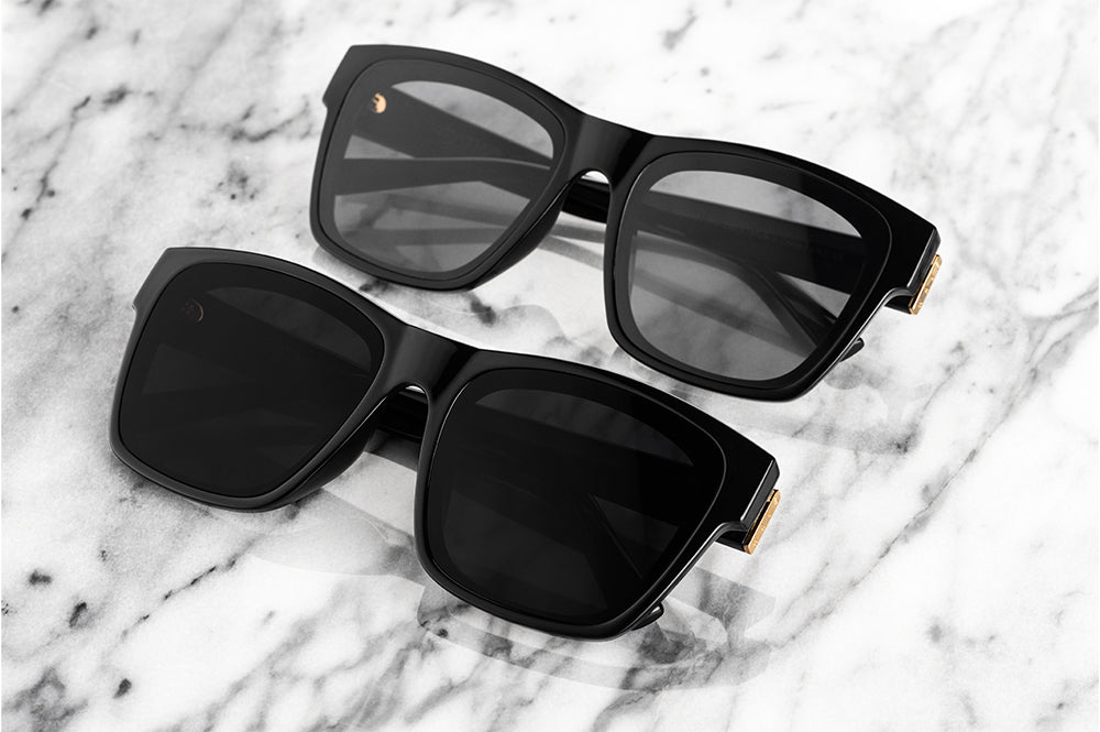 Lying on a marble table is the Clarity Ultra Black Sunglasses in comparison with the Clarity Black Sunglasses.