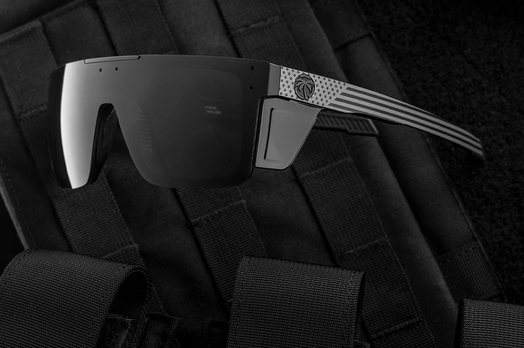 Close up of Heat Wave Performance Quatro black safety glasses with Socom USA Flag arms with bullet proof vest behind them.