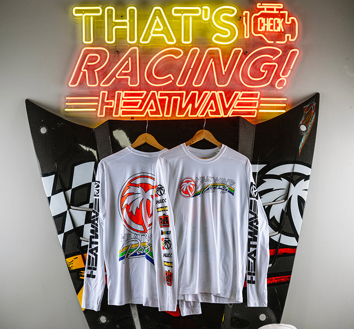 Hanging under a neon Heat Wave sign is the Heat Wave Visual Trading Paint White UPF Longsleeve.
